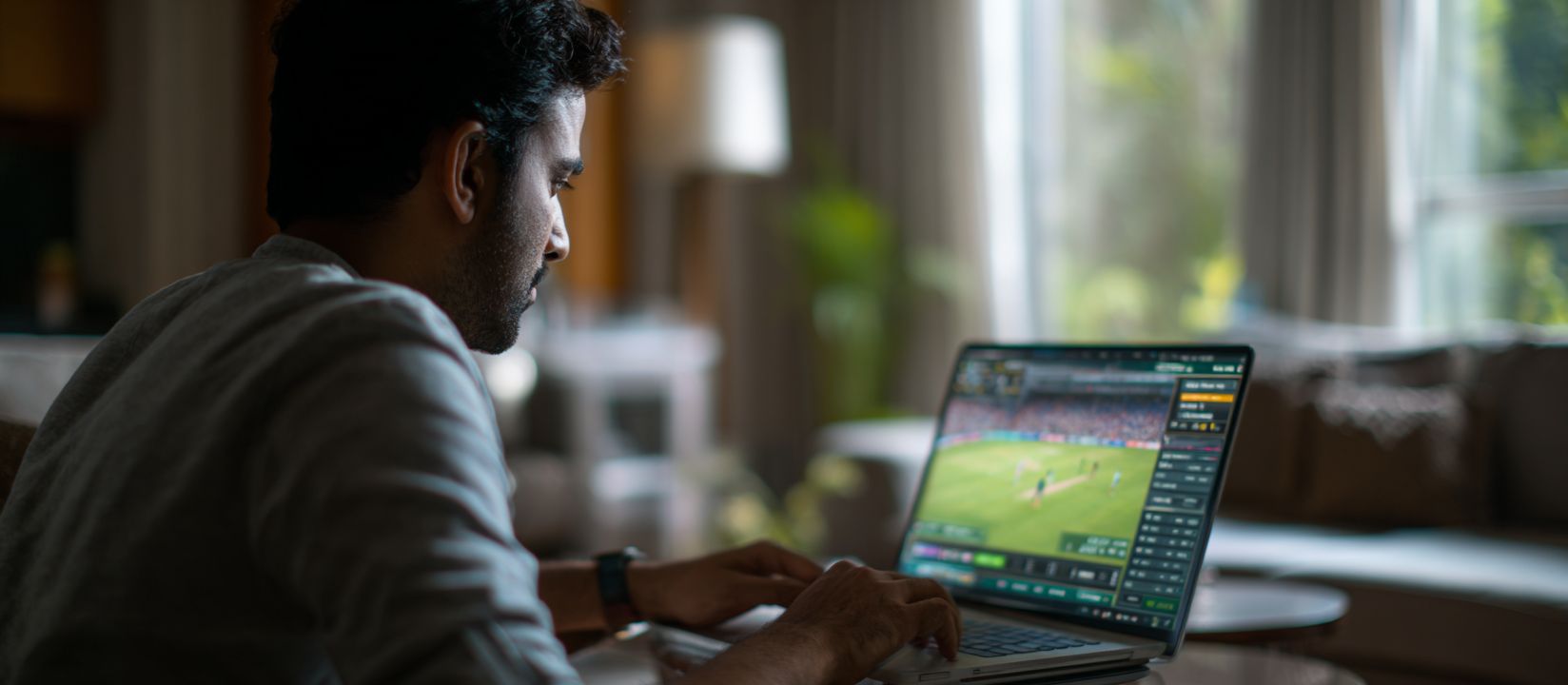 CV333 Bet – The ultimate choice for online sports betting in Bangladesh Focused man placing live cricket bets on CV333 sports platform using a laptop at home.
